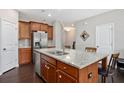 Open kitchen with granite counters, island with barstool seating, stainless appliances, and wood cabinets at 1427 Lanier Vista Dr, Sugar Hill, GA 30518