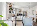 This bright kitchen features white cabinets, an island, stainless appliances, stone countertops, and updated lighting at 4568 Oswood Ct, Tucker, GA 30084