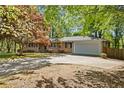 Brick home with attached garage and circular drive, nestled among mature trees at 1618 Cooper Lake Se Rd, Smyrna, GA 30082