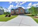 Traditional brick home with a concrete driveway and lush green lawn, set against a wooded backdrop at 404 Prague Way, Hampton, GA 30228
