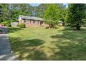 Well-manicured front yard with lush green grass, mature trees, and a brick home at 3127 Hidden Forest Dr, Snellville, GA 30078