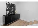 Hallway featuring a black textured cabinet with silver handles, contemporary art, and hardwood flooring at 108 Vinings Forest Se Cir, Smyrna, GA 30080