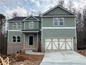 Inviting two-story home with green siding, a two-car garage, and a covered front porch at 66 Pine Creek Ct, Dallas, GA 30157
