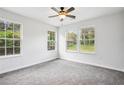 Bright bedroom featuring three large windows, plush carpet, and a modern ceiling fan at 961 Old Conyers Rd, Stockbridge, GA 30281