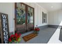 Inviting front porch featuring double doors, a 'Welcome' mat, and potted red flowers at 5138 Price Dr, Suwanee, GA 30024