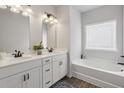 Bright bathroom features double sinks, white cabinets, and a tub with a shower, complemented by warm lighting at 375 Crider Ct, Woodstock, GA 30188