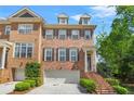 Beautiful brick townhome featuring a two-car garage and charming architectural details with stairs leading up to the front door at 1561 Mosaic Way, Smyrna, GA 30080
