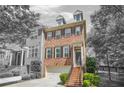 Beautiful brick townhome featuring a two-car garage and charming architectural details with stairs leading up to the front door at 1561 Mosaic Way, Smyrna, GA 30080