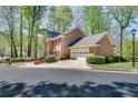 View of the side and front of a brick home with lush landscaping and an attached two car garage at 1826 Bedfordshire Ct, Decatur, GA 30033