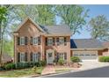 Beautiful brick home featuring a two-car garage, front garden and manicured lawn, situated among mature trees at 1826 Bedfordshire Ct, Decatur, GA 30033
