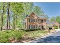 A well-kept two-story brick house with a manicured lawn sits among tall trees under a clear sky at 1826 Bedfordshire Ct, Decatur, GA 30033