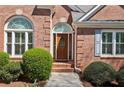 Elegant brick home entrance featuring an arched window, decorative sidelights, and manicured shrubs at 3925 Waterford Dr, Suwanee, GA 30024