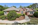 Beautifully landscaped brick home with a curved walkway, lush green bushes, and an arched window feature at 3925 Waterford Dr, Suwanee, GA 30024