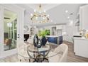 Stylish dining area featuring a glass table, modern chandelier, and views into the kitchen and living room at 1019 Cooks Farm Way, Woodstock, GA 30189
