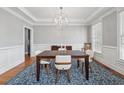 Elegant dining room featuring hardwood floors, wainscoting, a modern chandelier, and natural light at 1754 Water Springs Way, Dacula, GA 30019