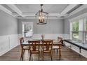 Dining room with a wood table and chairs, decorative lighting, coffered ceiling, wainscoting, and large windows at 505 Bryson Lake Cir, Douglasville, GA 30134