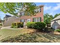 Traditional two-story brick home featuring a well-kept front lawn, trimmed bushes, and a cozy, welcoming entrance at 3978 Oak Crossing Drive Dr, Suwanee, GA 30024