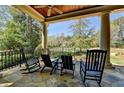 Relaxing covered porch features stone flooring, stately pillars and comfortable seating overlooking a serene view at 4505 Whitestone Way, Suwanee, GA 30024