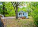 Quaint cottage-style home with blue siding, a white porch, and ample green space, creating a serene setting at 8211 Thompson St, Douglasville, GA 30134