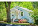 Attractive light blue home with white trim, a welcoming porch, and colorful landscaping with mature trees at 8211 Thompson St, Douglasville, GA 30134