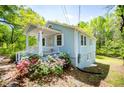Side view of a cozy blue house featuring a covered porch, white trim, and vibrant pink flowers in the yard at 8211 Thompson St, Douglasville, GA 30134