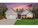 Charming single-story home with a two-car garage, well-manicured lawn, and fresh landscaping at dusk at 1195 Awenasa Dr, Villa Rica, GA 30180