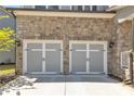 Close-up of a two-car garage featuring gray doors, stone facade, and decorative black hardware at 5382 Pebblebrook Se Ln, Mableton, GA 30126