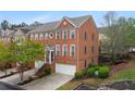 Attractive three-story brick townhome with attached garage, landscaped front yard, and welcoming entryway stairs at 4880 Payson Se Ter, Atlanta, GA 30339