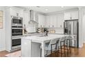 Modern kitchen with white cabinetry, stainless steel appliances, large island with seating, and hardwood floors at 185 Vandiver Ct, Acworth, GA 30101