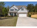 Inviting two-story home with gray siding, brick details, a two-car garage, and a spacious driveway leading to the property at 2034 W Hampton Dr, Canton, GA 30115