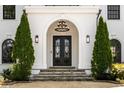 Grand entrance featuring a black wrought-iron double door, stone steps, and manicured evergreens at 725 Riley Pl, Atlanta, GA 30327