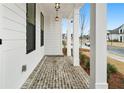 Inviting front porch with classic brick flooring, white columns and craftsman style lighting at 535 Pearl St, Cumming, GA 30040