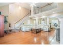 Spacious living room with high ceilings, a staircase, hardwood floors and white couches at 4505 Lakefield Bnd, Berkeley Lake, GA 30096