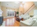 Sun-lit living room featuring hardwood floors, a fireplace and large windows with white couches at 4505 Lakefield Bnd, Berkeley Lake, GA 30096