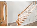 Bright foyer with a wood door and a staircase featuring white risers and wood handrail leading to the upper level at 4505 Lakefield Bnd, Berkeley Lake, GA 30096