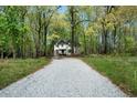 View down long driveway to a charming two-story home surrounded by mature trees at 7771 A C Smith Rd, Cumming, GA 30028