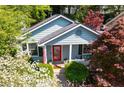Inviting exterior view of a light blue home with a red door, surrounded by lush greenery and blooming flowers at 777 Antone Nw St, Atlanta, GA 30318