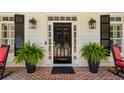 Elegant black front door framed by sidelights, decorative lanterns, and lush potted ferns on a brick porch at 155 Palmer Oaks Ln, Marietta, GA 30068