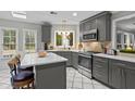 Well-lit kitchen featuring white tile floors, gray cabinets, stainless appliances and breakfast bar with sleek design at 5663 Brookstone Nw Dr, Acworth, GA 30101