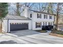 Side view of a two-story home with a two-car garage, black shutters, and a well-manicured lawn at 5465 N Fork Sw Dr, Lilburn, GA 30047