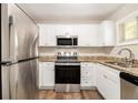 Bright kitchen featuring stainless steel appliances, granite countertops, and white cabinets at 1667 Hollyhock Ter, Decatur, GA 30032