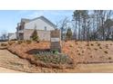 The Alcove Village brick community sign stands in front of a new home under construction at 1054 Georgian Point Dr, Lawrenceville, GA 30045