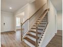 Modern staircase with wood steps, black metal railings, and natural light at 1054 Georgian Point Dr, Lawrenceville, GA 30045