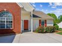Inviting front entrance with a red door, brick detailing, and well-manicured landscaping at 2265 Pemberton Pt, Buford, GA 30519