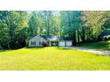 A single story home with a large grassy front yard and driveway, surrounded by mature trees at 3805 Forsythia Way, Douglasville, GA 30135