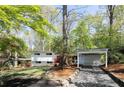 Mid-century modern home with a carport, mature trees, manicured lawn, and stone walkway at 1690 Cotswold Ne Dr, Brookhaven, GA 30319