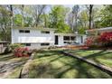 Charming home with a well-manicured lawn, blooming azaleas, and a stone retaining wall at 1690 Cotswold Ne Dr, Brookhaven, GA 30319