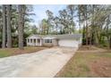 Ranch home with a charming front porch and attached garage, complemented by a long driveway and lush trees at 2000 Hill Rd, Marietta, GA 30062