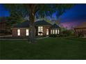 Brick home with large front yard featuring a mature tree, lit for nighttime appeal at 6382 Mountain Ridge Cir, Sugar Hill, GA 30518
