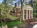 Elegant brick home with classic architectural details, surrounded by mature trees and lush greenery at 1961 River Forest Rd, Atlanta, GA 30327